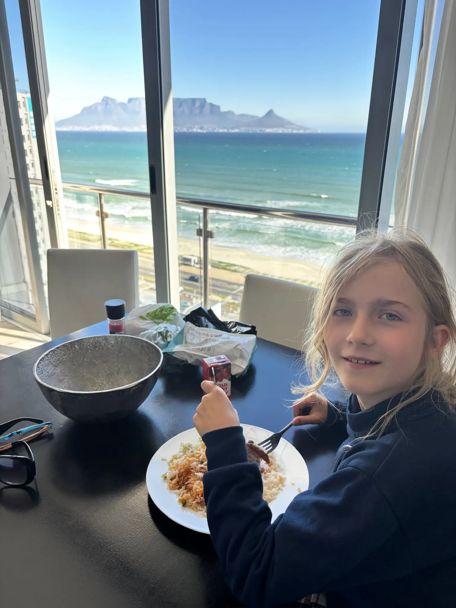 Merle isst am Tisch, im Fenster das Tafelberg-Panorama