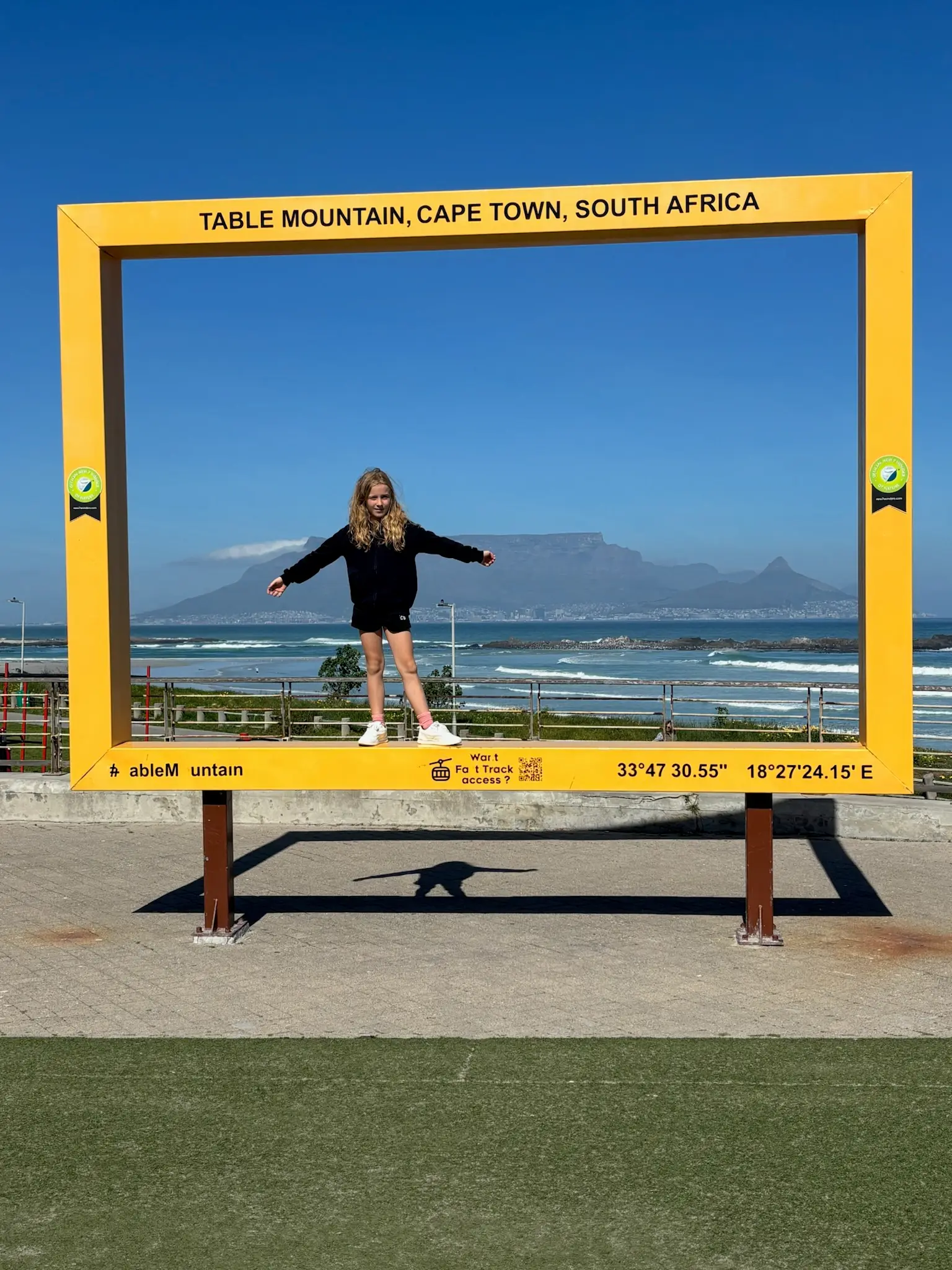 Merle steht in einem gelben Bilderrahmen, dahinter der Tafelberg